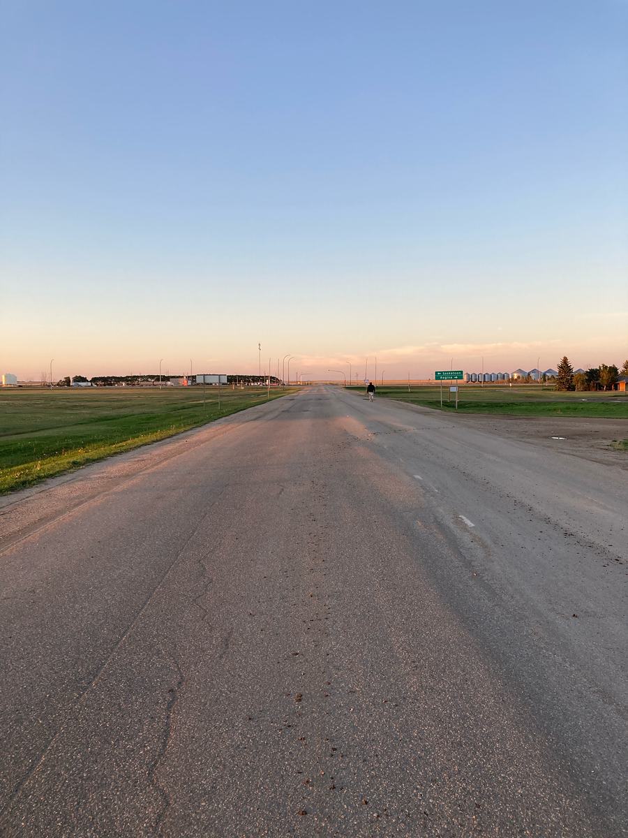 Una carretera vacía en la pradera que llega hasta el horizonte al anochecer, en Saskatchewan, Canadá.